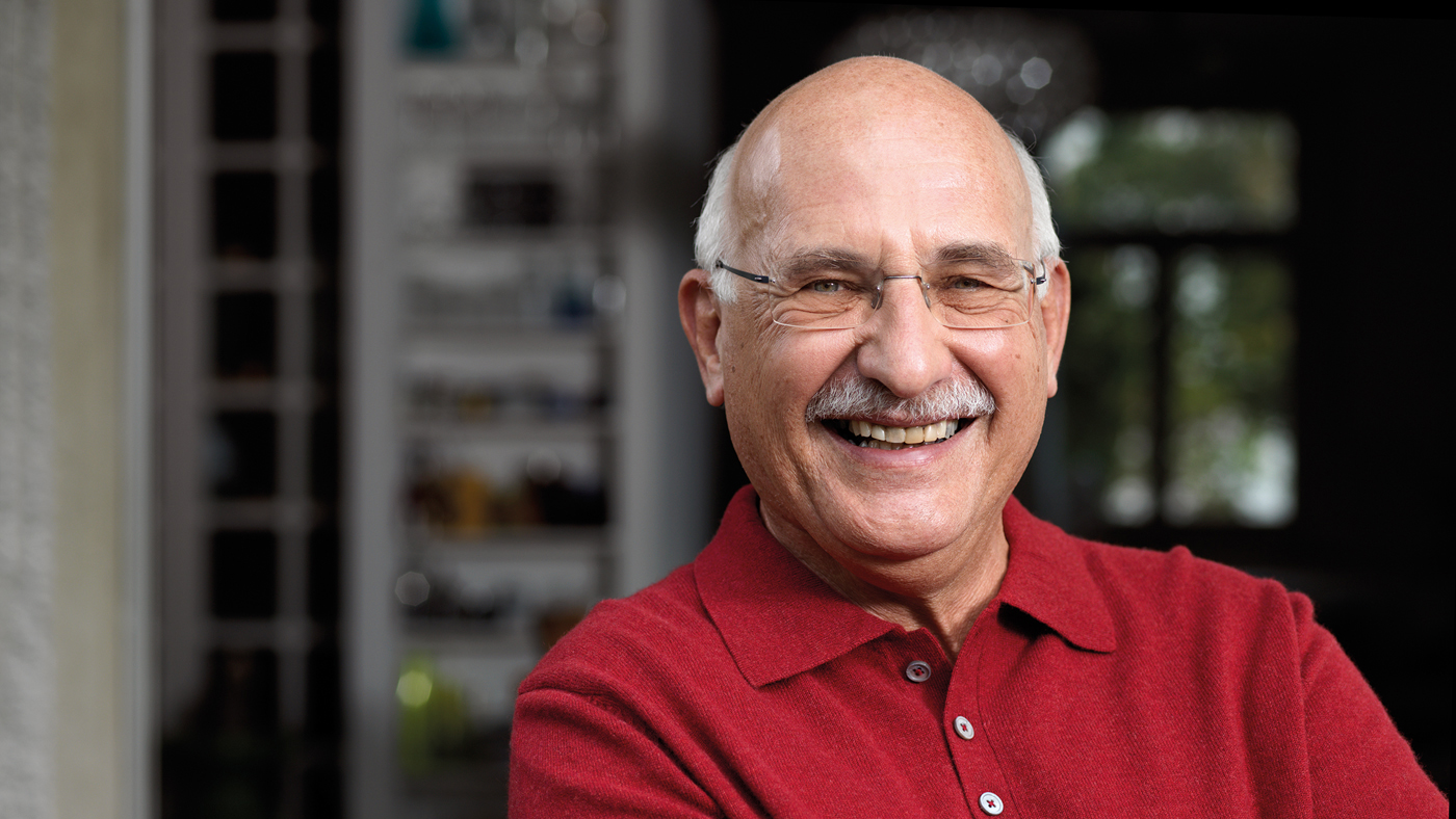 Ein Senior mit rotem T-shirt schaut in die Kamera und lächelt